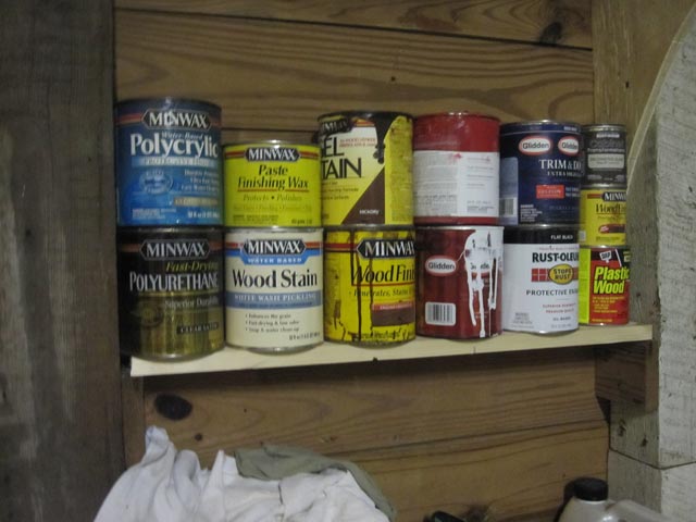 Shelf between stud holding wood stains and small paint cans