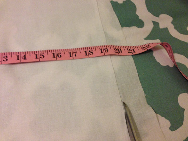 cutting white fabric using tape measure and scissors