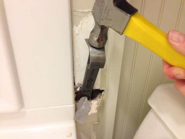hammer and small crowbar prying out damaged drywall