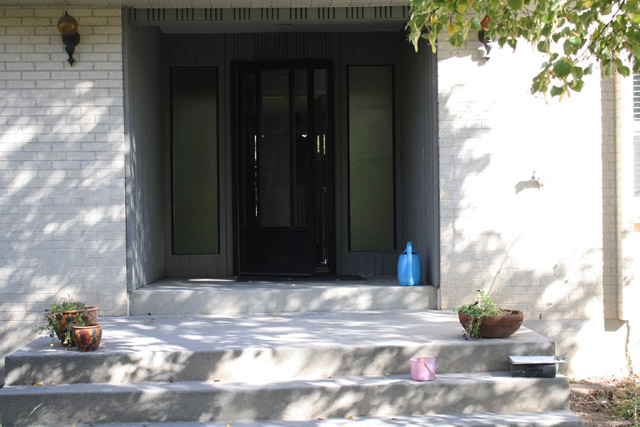 black front entry door with storm door and grey porch