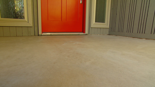 concrete porch after cleaning with red entry door and grey siding