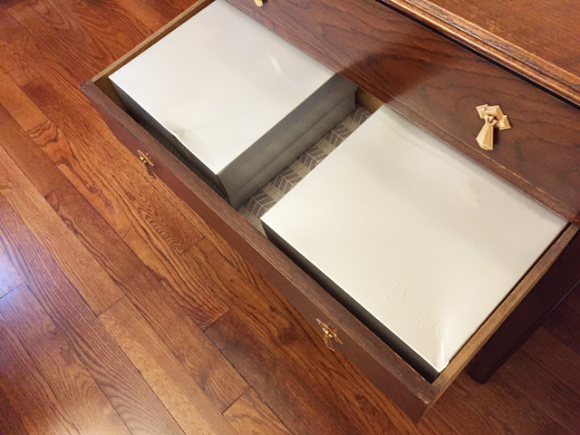 silver china plate boxes sitting in dresser drawer over hardwood floor