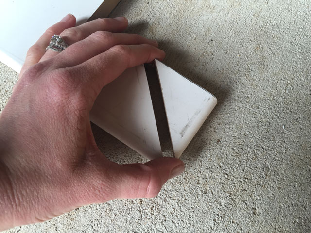 hand holding pieces of white window stool in place